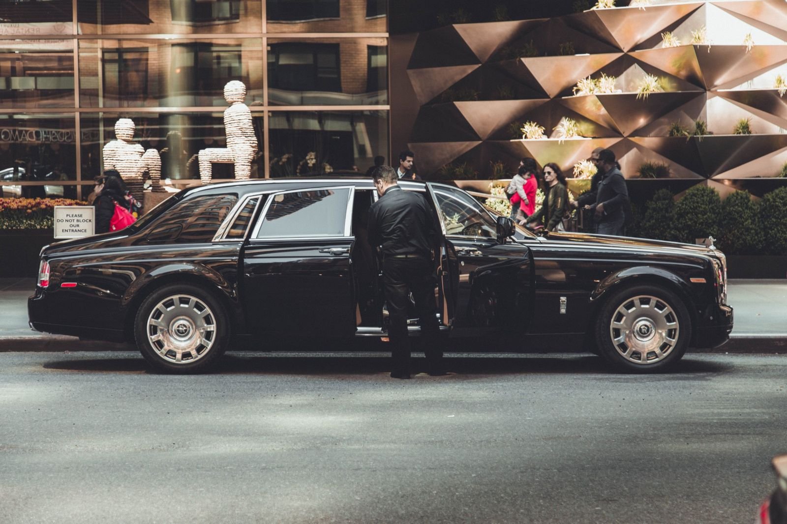 Chauffeur opening the door of a black luxury car